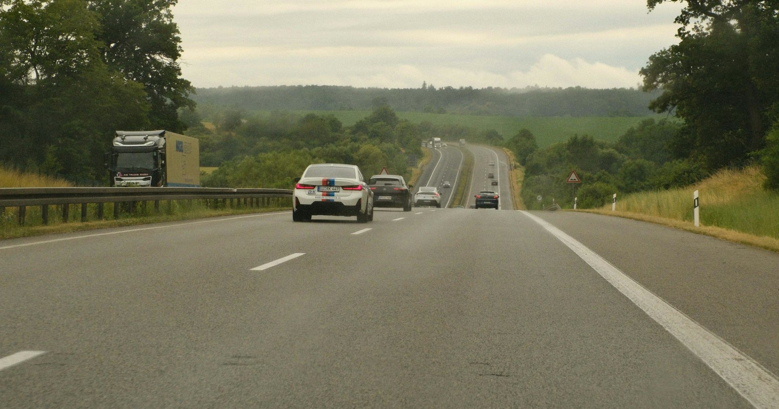 昼間の高速道路を走る複数の自動車、背景に緑の風景